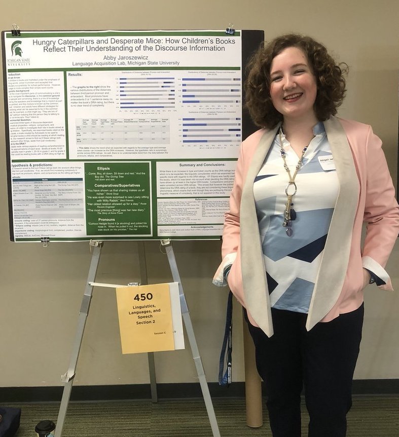 woman smiling next to poster detailing her research
