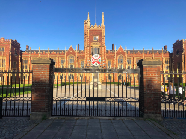 A tall brick building with classic architecture with a big gate in front of it.  