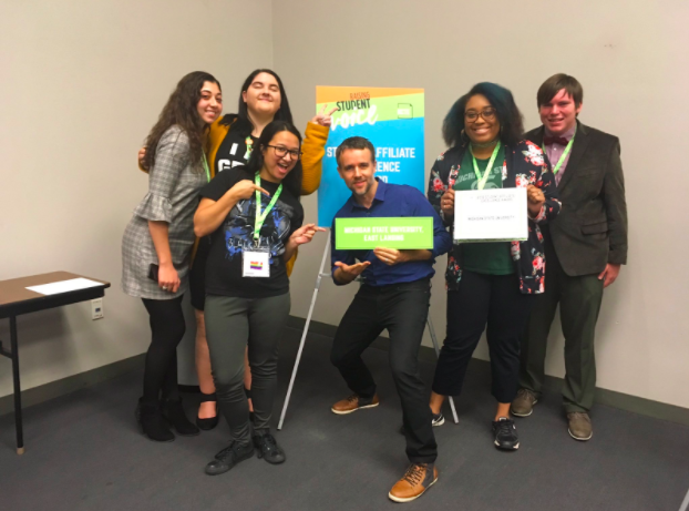 A group of very happy people are smiling as they win an award. 